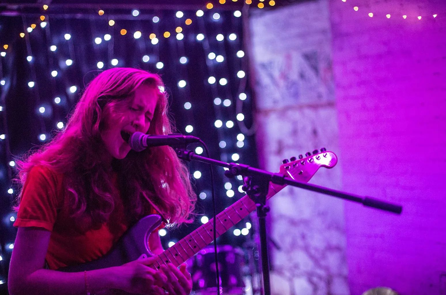 Sidney Gish playing guitar and singing into a microphone